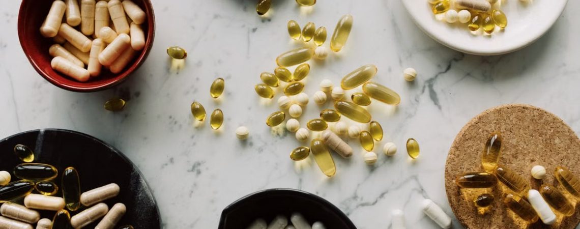Variety of capsules and pills displayed in bowls on a marble table, ideal for healthcare concepts.